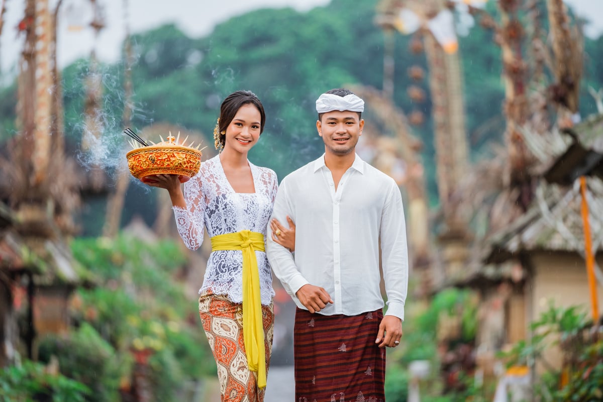 Smiling Balinese Couple Carrying an Holy Offering during Galungan Day